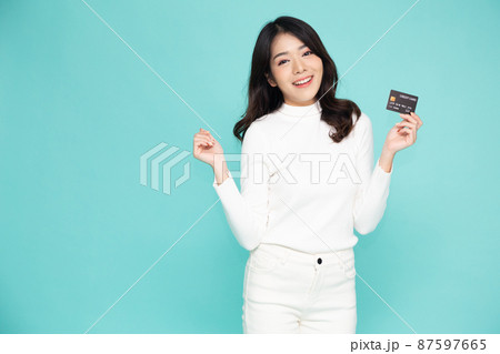 Young beautiful Asian woman smiling, showing, presenting credit card for making payment or paying online business, Pay a merchant or as a cash advance for goods, Cardholder or A person who owns a card Young beautiful Asian woman smiling, showing, presenting credit card for making payment or paying online business, Pay a merchant or as a cash advance for goods, Cardholder or A person who owns a card 87597665