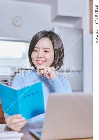 年金手帳を見つめて将来を考える若い女性 年金手帳を見つめて将来を考える若い女性 87597923