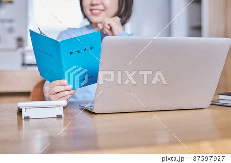 年金手帳を見つめて将来を考える若い女性 年金手帳を見つめて将来を考える若い女性 87597927
