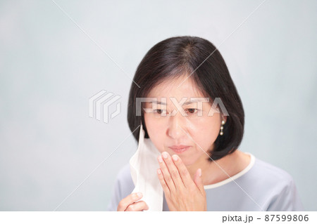 マスクを外して口に手をやる中年女性 口臭イメージ マスクを外して口に手をやる中年女性 口臭イメージ 87599806