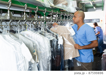 Man preparing garments for collection at dry-cleaning Man preparing garments for collection at dry-cleaning 87599896
