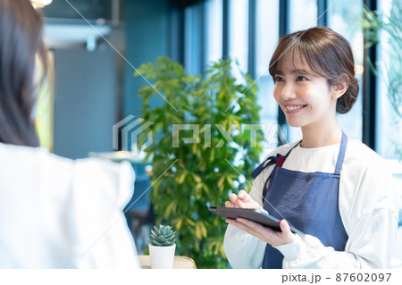 お団子ヘアで注文を受けるカフェの若い女性店員 お団子ヘアで注文を受けるカフェの若い女性店員 87602097