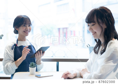 タブレット端末で注文を受ける若い女性店員 87602300