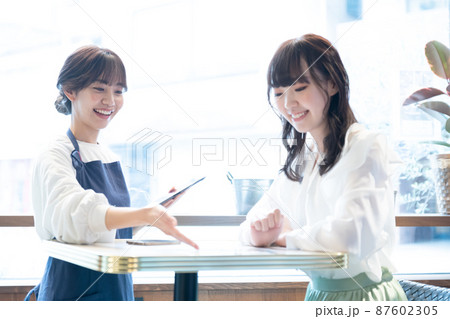 タブレット端末で注文を受ける若い女性店員 タブレット端末で注文を受ける若い女性店員 87602305
