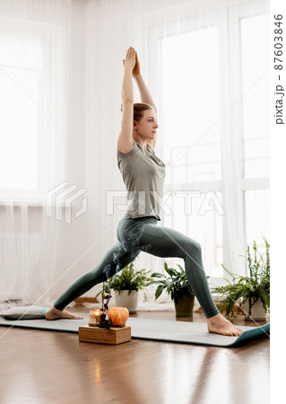 Beautiful young woman doing exercises and doing yoga at home 87603846