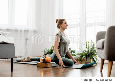 Beautiful young woman doing exercises and doing yoga at home 87603848