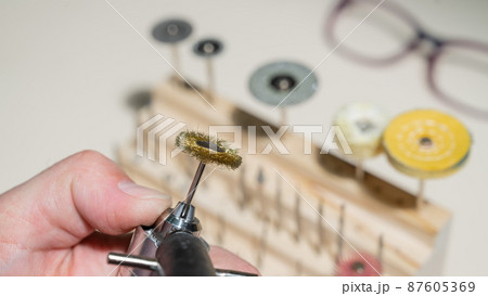 An optician technician polishes the frame of glasses. A professional optician fixes glasses. 87605369