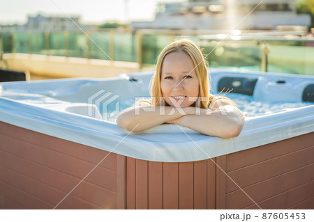 Portrait of young carefree happy smiling woman relaxing at hot tub during enjoying happy traveling moment vacation life against the background of green big mountains 87605453