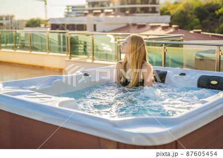 Portrait of young carefree happy smiling woman relaxing at hot tub during enjoying happy traveling moment vacation life against the background of green big mountains Portrait of young carefree happy smiling woman relaxing at hot tub during enjoying happy traveling moment vacation life against the background of green big mountains 87605454