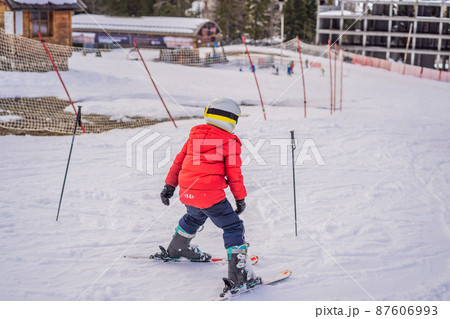 Child skiing in mountains. Active toddler kid with safety helmet, goggles and poles. Ski race for young children. Winter sport for family. Kids ski lesson in alpine school. Little skier racing in snow Child skiing in mountains. Active toddler kid with safety helmet, goggles and poles. Ski race for young children. Winter sport for family. Kids ski lesson in alpine school. Little skier racing in snow 87606993