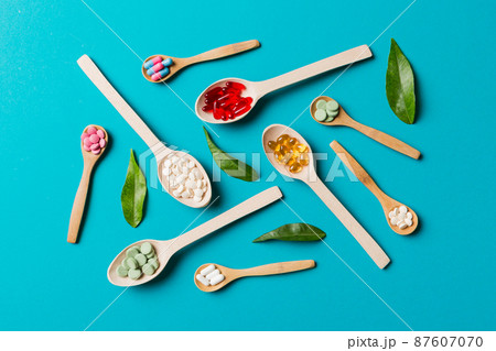 Top view Variety of vitamin and mineral pills in wooden spoon on Colored background. Top view of assorted pharmaceutical medicine pills. Dietary supplement healthcare product Top view Variety of vitamin and mineral pills in wooden spoon on Colored background. Top view of assorted pharmaceutical medicine pills. Dietary supplement healthcare product 87607070