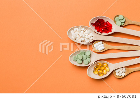 Top view Variety of vitamin and mineral pills in wooden spoon on Colored background. Top view of assorted pharmaceutical medicine pills. Dietary supplement healthcare product Top view Variety of vitamin and mineral pills in wooden spoon on Colored background. Top view of assorted pharmaceutical medicine pills. Dietary supplement healthcare product 87607081