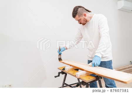 the carpenter covers the wood with oil with a brush. the carpenter covers the wood with oil with a brush. 87607381