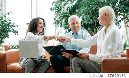 two business ladies shaking hands sitting in the office lobby. 87609123