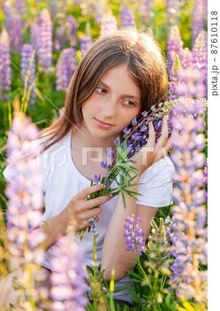 Happy teenage girl smiling outdoor. Beautiful young teen woman resting on summer field with blooming wild flowers green background. Free happy kid teenager girl, childhood concept Happy teenage girl smiling outdoor. Beautiful young teen woman resting on summer field with blooming wild flowers green background. Free happy kid teenager girl, childhood concept 87610118