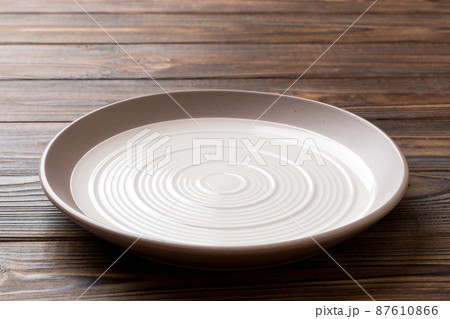 Perspective view of empty light plate on wooden background. Empty space for your design 87610866