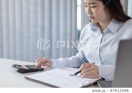 Businesswoman presses a calculator to calculate earnings and analyze company earnings in his private office, Information in finance and accounting, Company performance and revenue. Businesswoman presses a calculator to calculate earnings and analyze company earnings in his private office, Information in finance and accounting, Company performance and revenue. 87612098