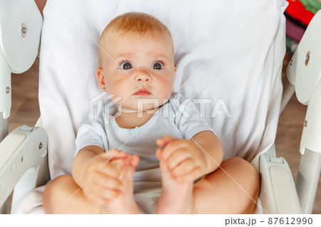 Cute little newborn girl with smiling face looking at camera on white background. Infant baby resting playing lying down on feeding chair at home. Motherhood happy child concept 87612990