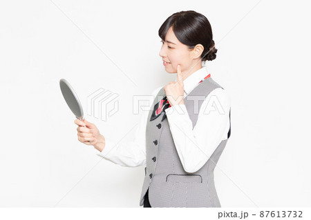 白い背景の前に立って手鏡で肌をチェックするビジネスウーマン 白い背景の前に立って手鏡で肌をチェックするビジネスウーマン 87613732