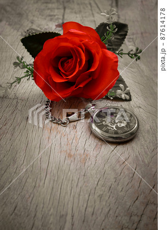 Red rose flower and A retro pocket watch on old wooden board background. Red rose flower and A retro pocket watch on old wooden board background. 87614178
