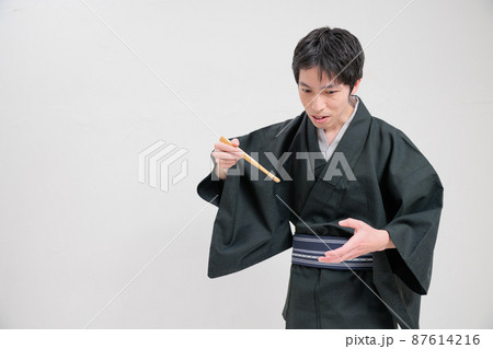 扇子を使って食べる物まねをする落語家 87614216