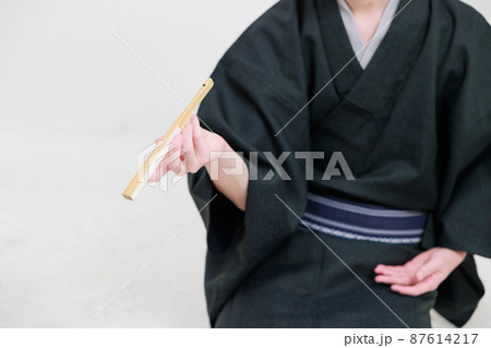 扇子を使ってタバコを吸うモノマネをする落語家 87614217