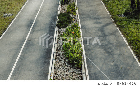Top view of empty road texture with median strip in the middle surrounded green grass. 87614456