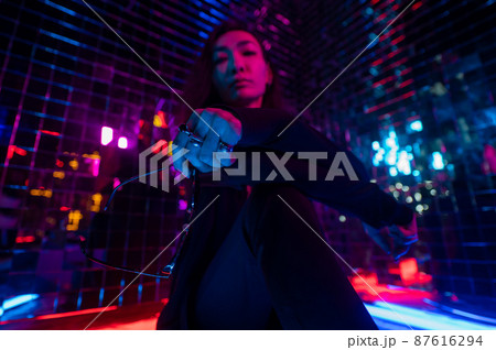Asian man holding sunglasses. Neon photo studio.  87616294