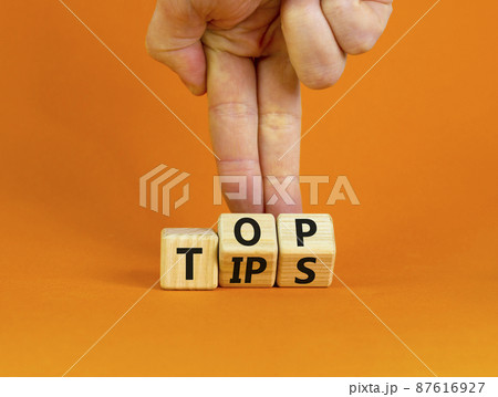 Top tips symbol. Businessman turns wooden cubes with words 'Top tips'. Beautiful orange background. Top tips and business concept. Copy space. Top tips symbol. Businessman turns wooden cubes with words 'Top tips'. Beautiful orange background. Top tips and business concept. Copy space. 87616927