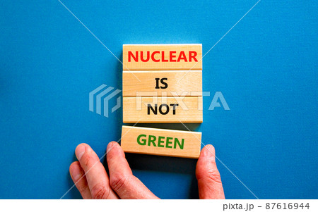 Nuclear is not green symbol. Concept words Nuclear is not green on wooden blocks. Businessman hand. Beautiful blue table blue background. Nuclear is not green business concept. Copy space. Nuclear is not green symbol. Concept words Nuclear is not green on wooden blocks. Businessman hand. Beautiful blue table blue background. Nuclear is not green business concept. Copy space. 87616944
