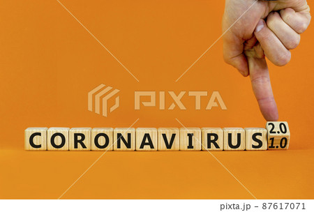 Covid-19 coronavirus 2.0 symbol. Doctor turns cubes and changes words coronavirus 1.0 to coronavirus 2.0. Beautiful orange background copy space. Medical Covid-19 coronavirus 1.0 or 2.0 concept. 87617071