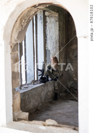 Caucasian military woman in a destroyed building. Caucasian military woman in a destroyed building. 87618102
