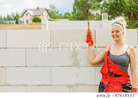 Woman using string as level in wall construction. Woman using string as level in wall construction. 87618532