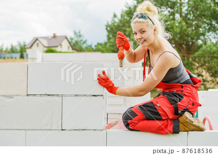 Woman using string as level in wall construction. Woman using string as level in wall construction. 87618536