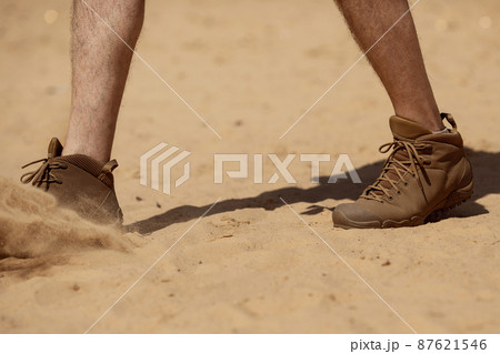 Close up of man legs walking in tactical shoes on sand surface Close up of man legs walking in tactical shoes on sand surface 87621546