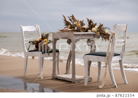 A table  designed for a boho style event with an eucalyptus, vintage plates and other rustic touches. On seaside in the sand 87621554