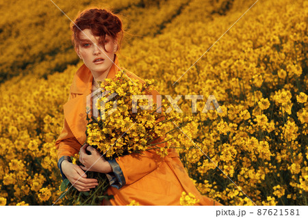 Young fashion model portrait with ginger hair and blue eyes in yellow rapeseed field. Spring concept Young fashion model portrait with ginger hair and blue eyes in yellow rapeseed field. Spring concept 87621581