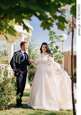 bride and groom walk holding hands through park by the rotunda. wedding walk.  87623005