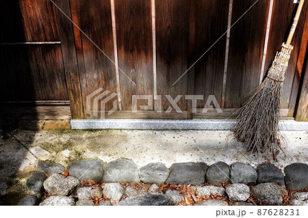 小屋の壁に立て掛けられた竹箒 87628231