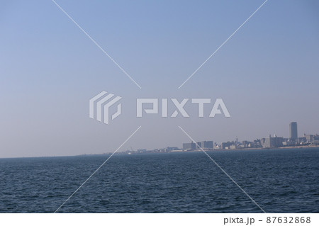 青空と青い海面の海の海岸沿いの都会の街並みの見える風景 87632868