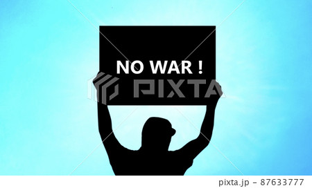 NO WAR!と書いたプラカードを持つ男性のシルエット_青空と光背景 87633777