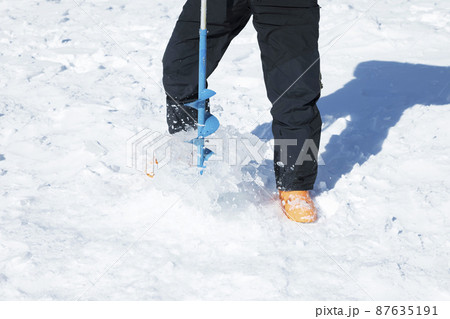 湖の氷に電動ドリルで穴をあける男性足元 ワカサギ釣りイメージ 湖の氷に電動ドリルで穴をあける男性足元 ワカサギ釣りイメージ 87635191