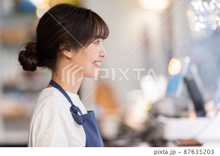カフェのカウンターで接客する若い女性店員 87635203