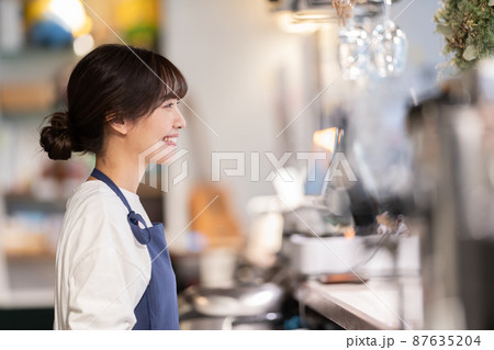 カフェのカウンターで接客する若い女性店員 カフェのカウンターで接客する若い女性店員 87635204