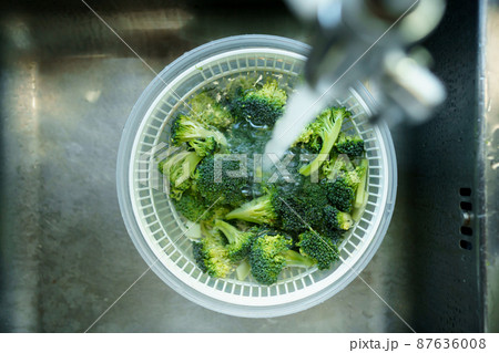 Washing an organic fresh vegetable before cooking. Washing prepared broccoli in the basket with water. 87636008