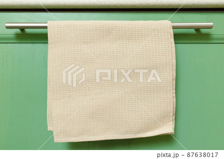 Waffle kitchen towel hanging on the doorknob of a home kitchen cabinet 87638017