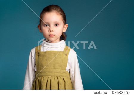 Cropped studio simple portrait of little kid girl 5 y.o. looking at camera over blue background Cropped studio simple portrait of little kid girl 5 y.o. looking at camera over blue background 87638255