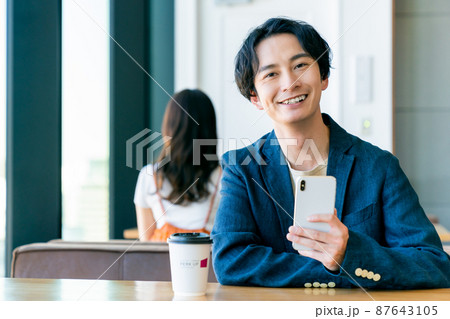カフェでスマホを見る若い男性 87643105