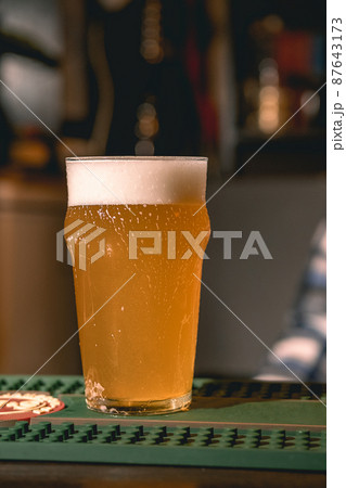 Glass of wheat beer served to client on bar counter in pub Glass of wheat beer served to client on bar counter in pub 87643173