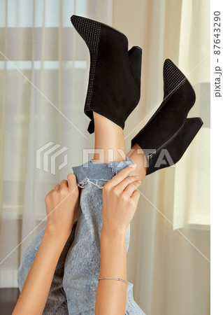 Raised up female legs in jeans and black suede ankle boots Raised up female legs in jeans and black suede ankle boots 87643290